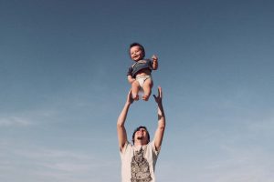 Man holding a baby up in the air.